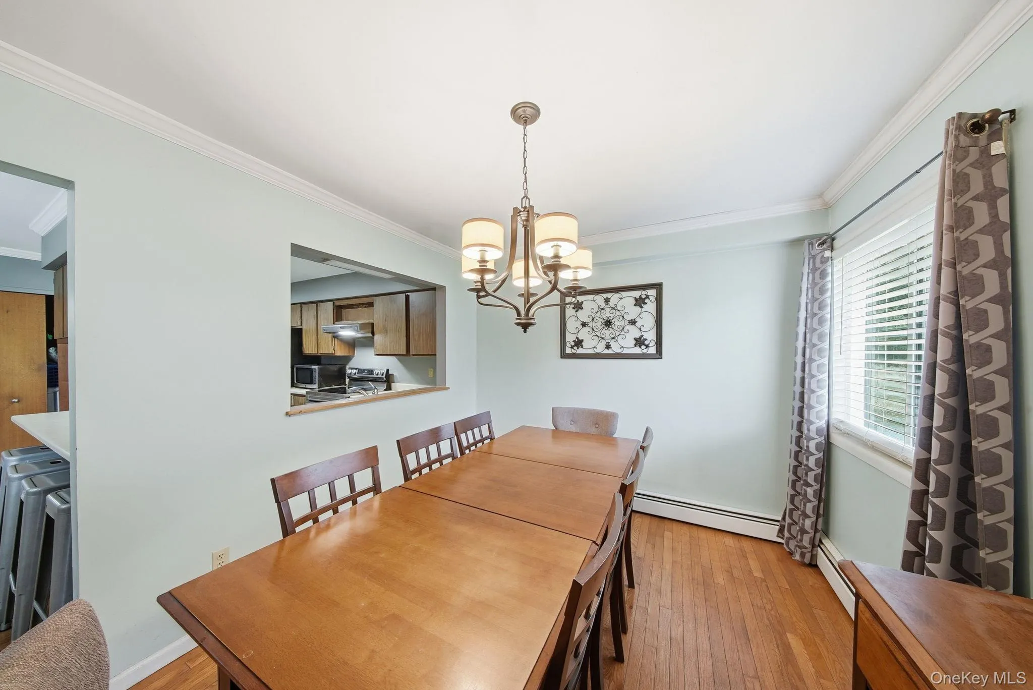 Dining space featuring ornamental molding, a chandelier, light wood-type flooring, and a baseboard radiator Dining space featuring ornamental molding, a chandelier, light wood-type flooring, and a baseboard radiator