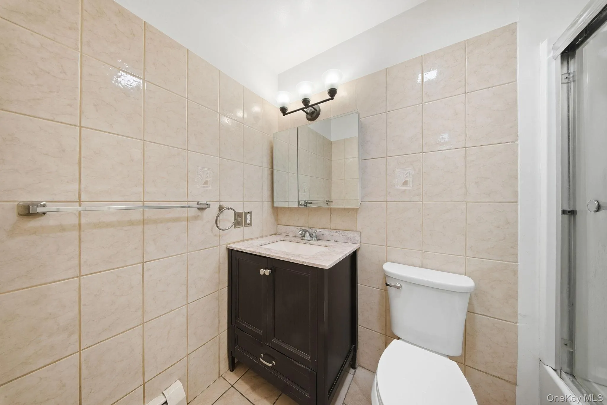 Bathroom with vanity, tile walls, and light tile patterned flooring Bathroom with vanity, tile walls, and light tile patterned flooring