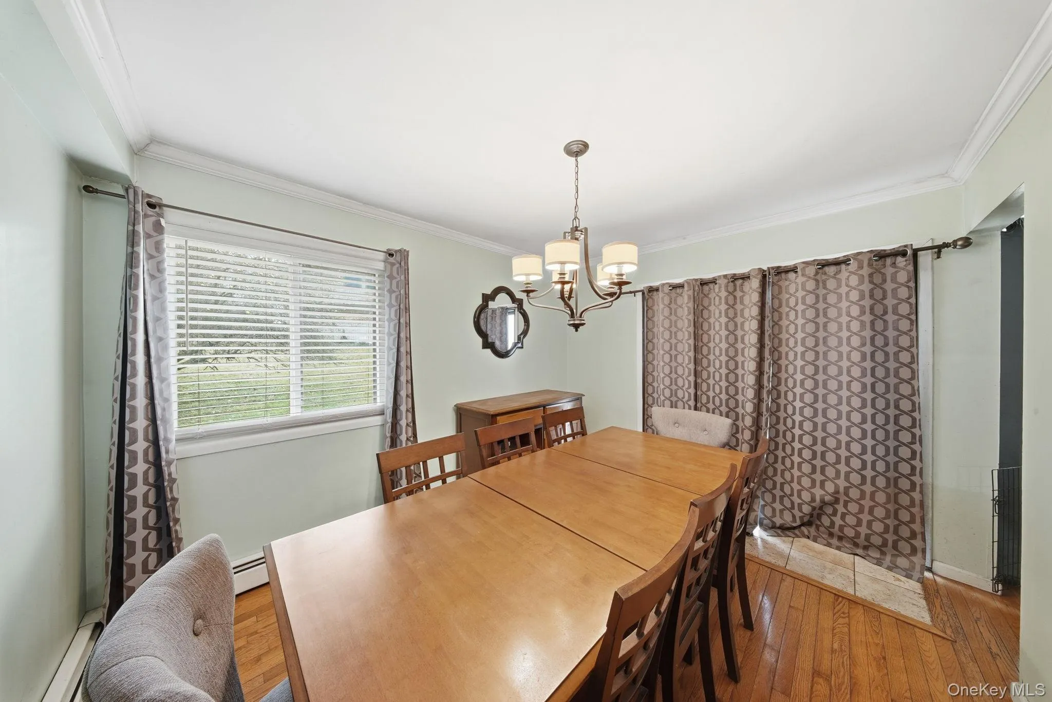 Dining area with crown molding, a baseboard radiator, a chandelier, and hardwood / wood-style flooring Dining area with crown molding, a baseboard radiator, a chandelier, and hardwood / wood-style flooring