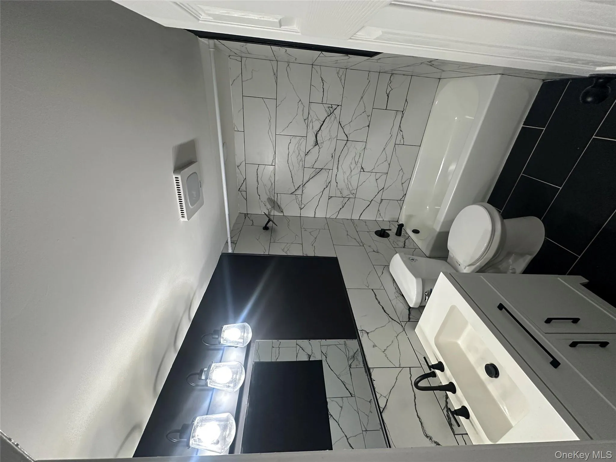 Bathroom with shower / tub combination, vanity, tile walls, dark tile patterned flooring, and backsplash Bathroom with shower / tub combination, vanity, tile walls, dark tile patterned flooring, and backsplash