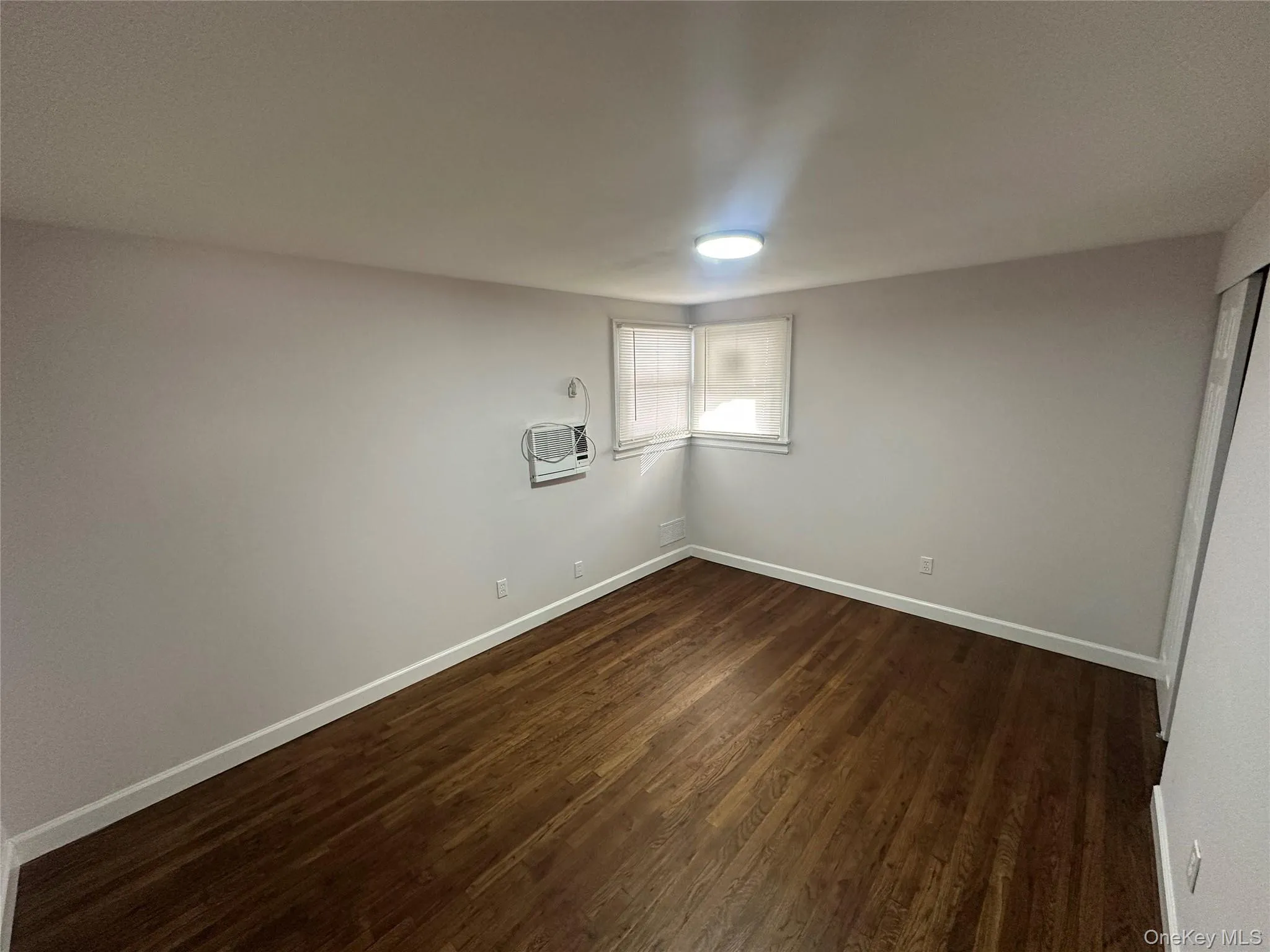 Unfurnished room featuring baseboards and dark wood-style flooring Unfurnished room featuring baseboards and dark wood-style flooring