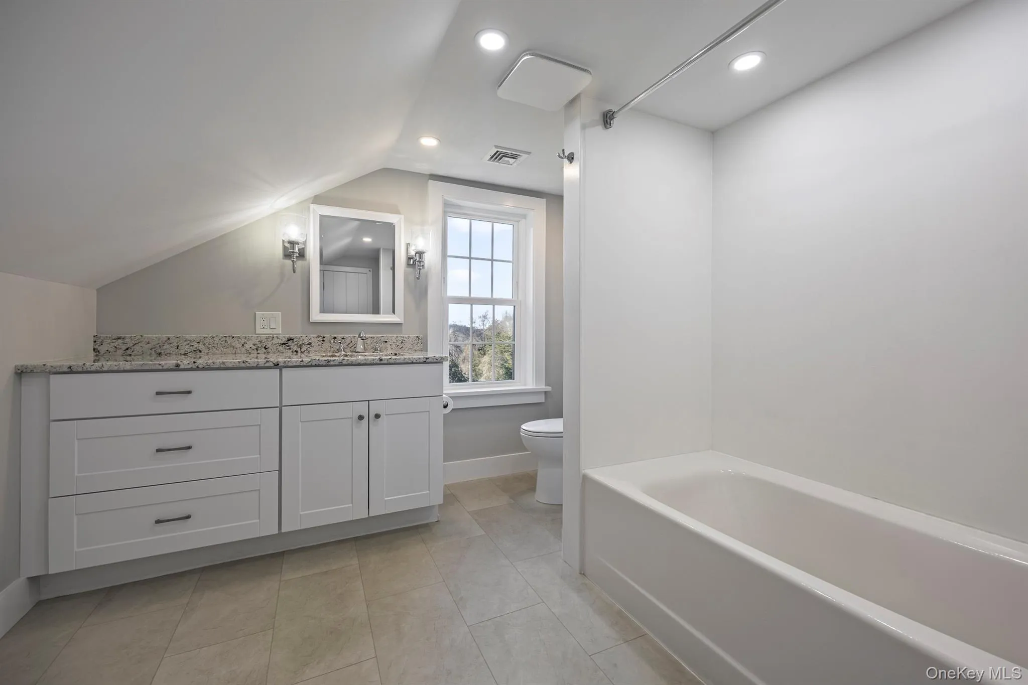 Full bath with vanity, a bathtub, lofted ceiling, recessed lighting, and light tile patterned floors Full bath with vanity, a bathtub, lofted ceiling, recessed lighting, and light tile patterned floors