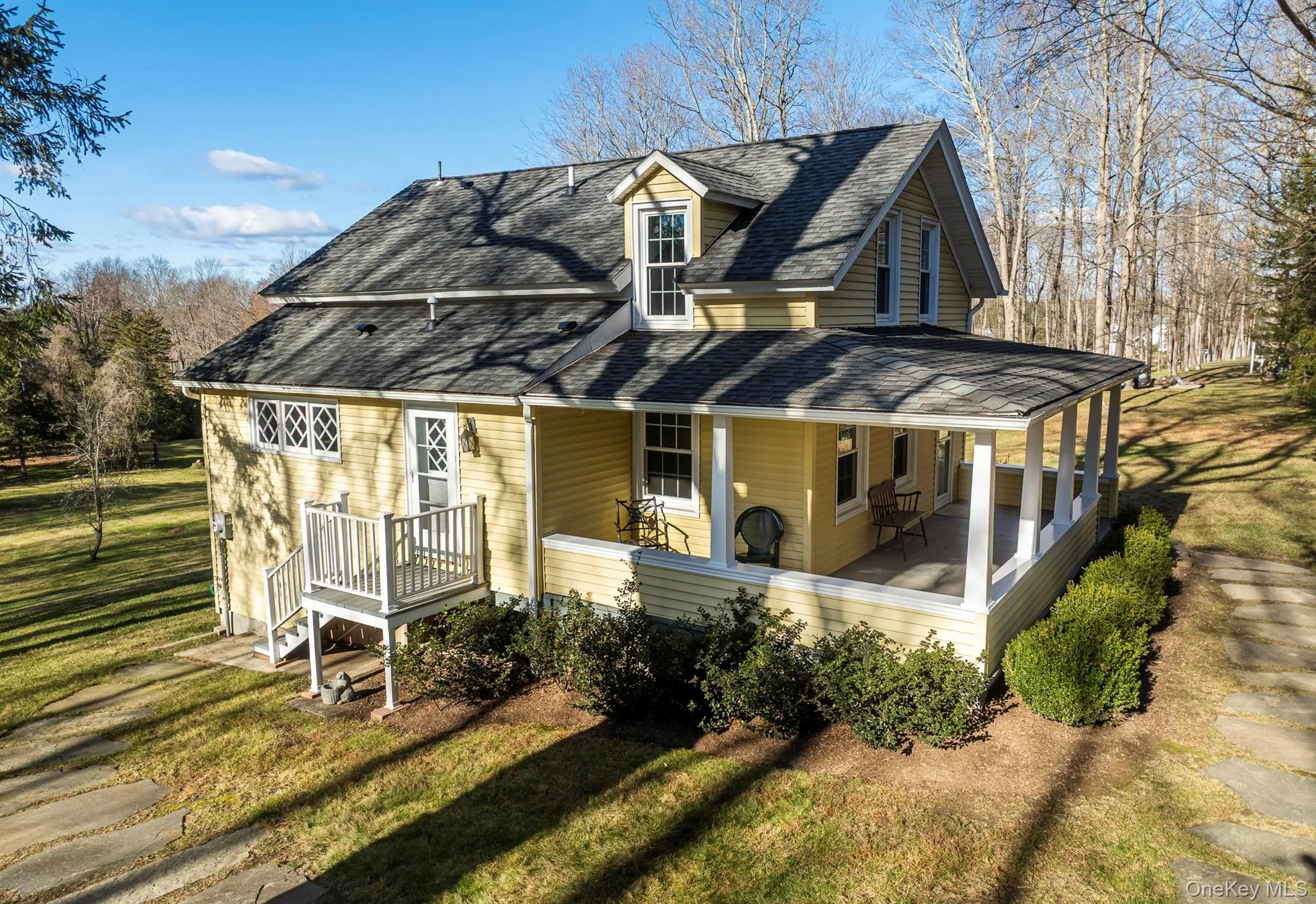 View of side corner of property featuring a porch, roof with shingles, and a front yard View of side corner of property featuring a porch, roof with shingles, and a front yard