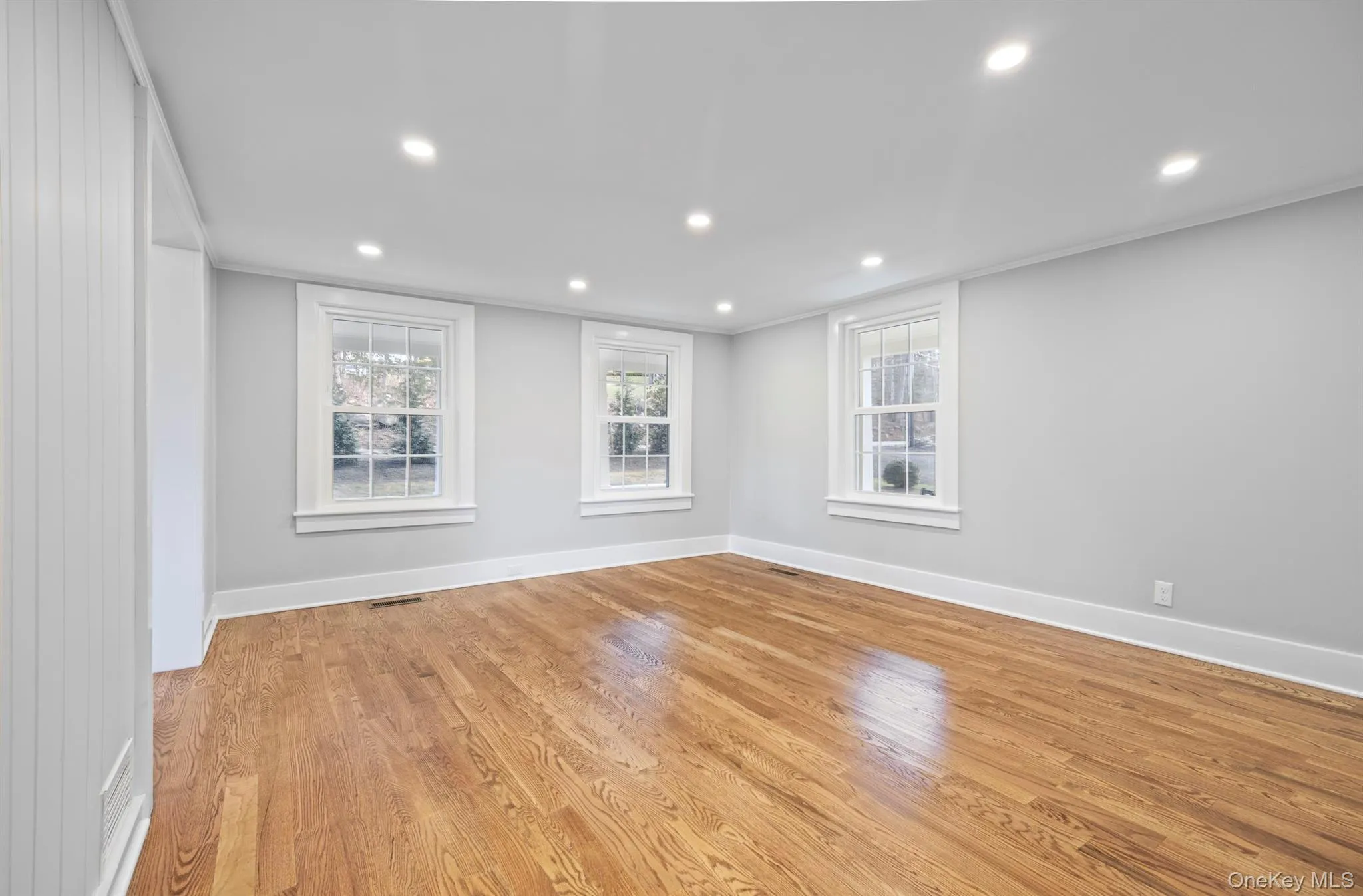 Living room with recessed lighting, plenty of natural light, wood finished floors, and crown molding Living room with recessed lighting, plenty of natural light, wood finished floors, and crown molding