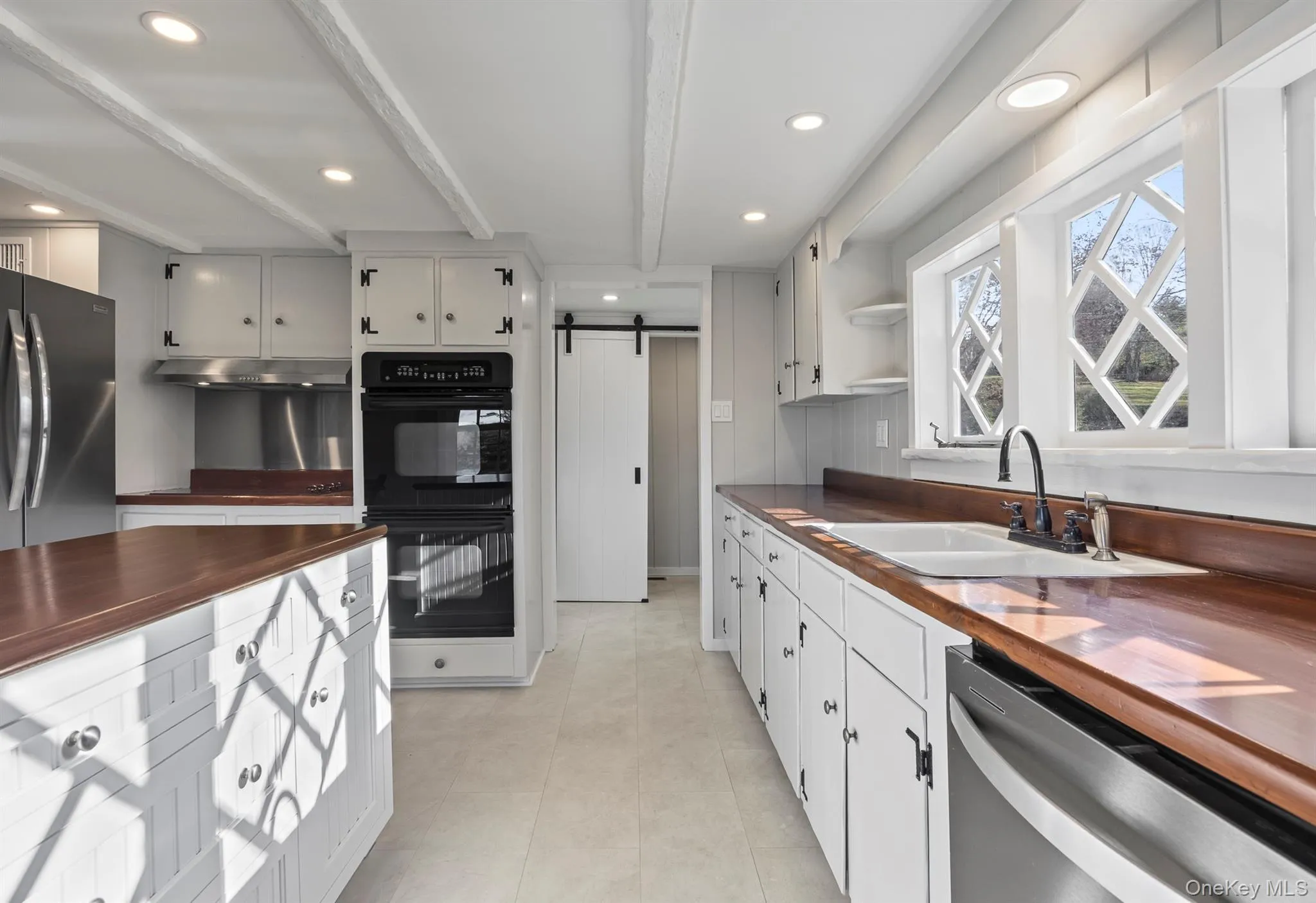 Kitchen featuring wooden counters, a barn door, appliances with stainless steel finishes, open shelves, and beam ceiling Kitchen featuring wooden counters, a barn door, appliances with stainless steel finishes, open shelves, and beam ceiling