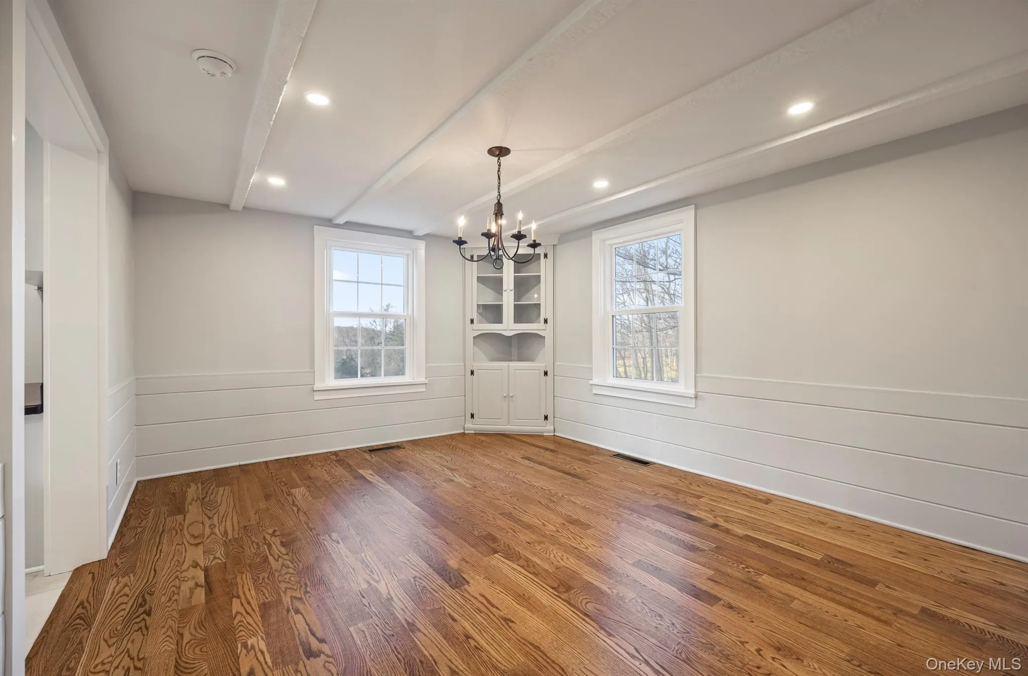 Dining room featuring a wainscoted wall, wood finished floors, a chandelier, beam ceiling, and recessed lighting Dining room featuring a wainscoted wall, wood finished floors, a chandelier, beam ceiling, and recessed lighting