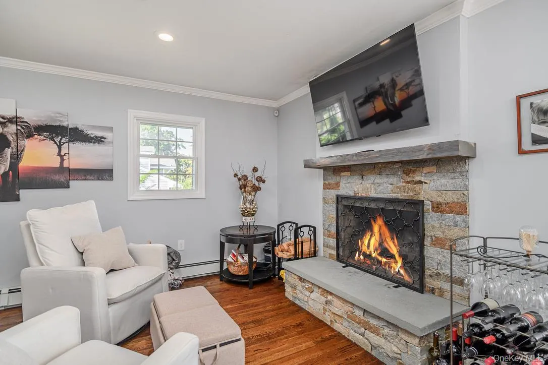 Living room featuring dark wood finished floors, a fireplace, a baseboard radiator, crown molding, and recessed lighting Living room featuring dark wood finished floors, a fireplace, a baseboard radiator, crown molding, and recessed lighting
