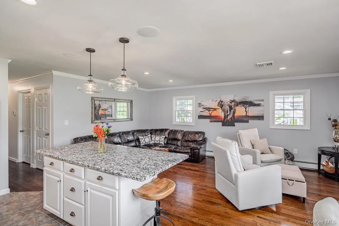 Kitchen with light stone countertops, a center island, white cabinetry, open floor plan, and crown molding Kitchen with light stone countertops, a center island, white cabinetry, open floor plan, and crown molding