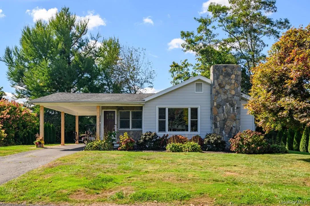 View of front of home featuring a carport, a front yard, asphalt driveway, covered porch, and a chimney View of front of home featuring a carport, a front yard, asphalt driveway, covered porch, and a chimney