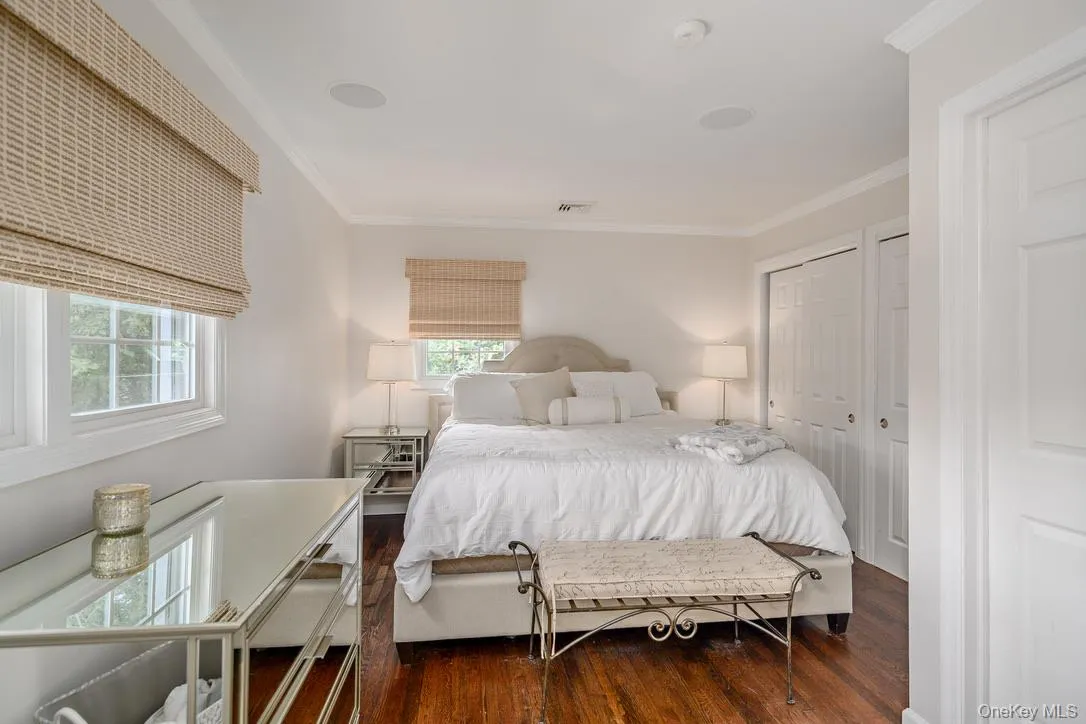 Bedroom featuring crown molding, wood-type flooring, and two closets Bedroom featuring crown molding, wood-type flooring, and two closets