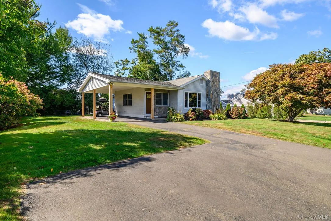 View of front of property featuring a carport, a front yard, driveway, a chimney, and a porch View of front of property featuring a carport, a front yard, driveway, a chimney, and a porch