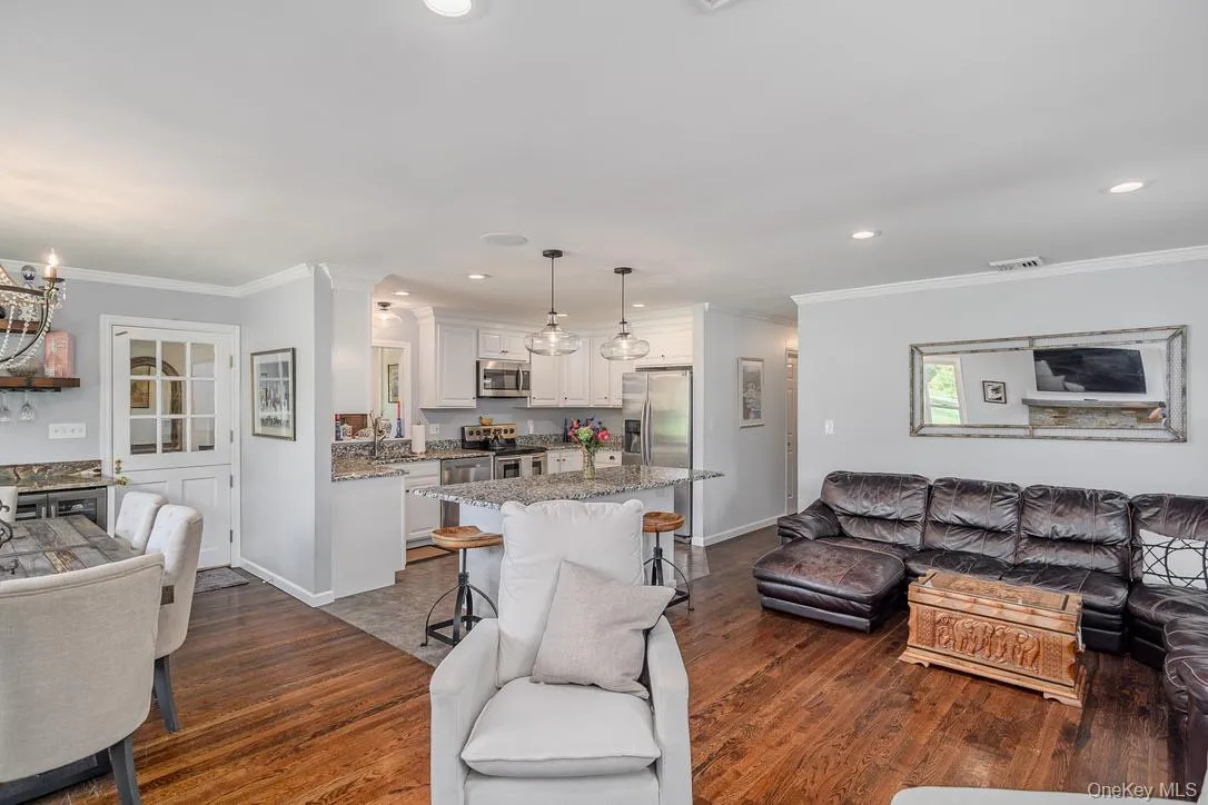 Living room with crown molding, recessed lighting, and dark wood-style flooring Living room with crown molding, recessed lighting, and dark wood-style flooring