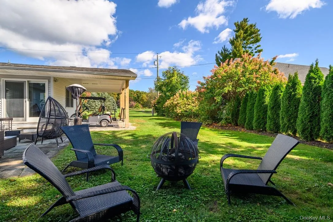 View of grassy yard featuring an outdoor fire pit and a patio area View of grassy yard featuring an outdoor fire pit and a patio area