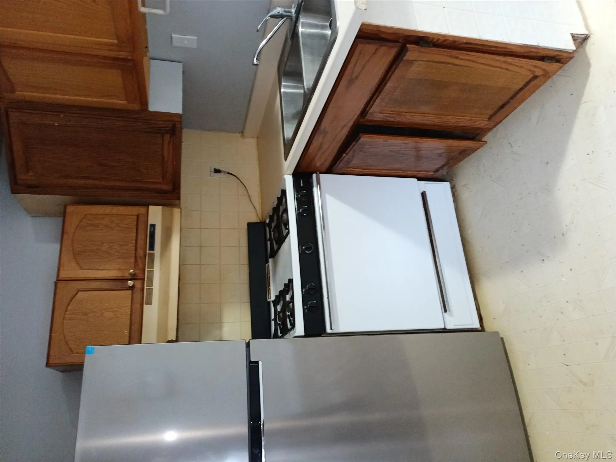 Kitchen with light flooring, refrigerator, white gas range oven, and light countertops Kitchen with light flooring, refrigerator, white gas range oven, and light countertops