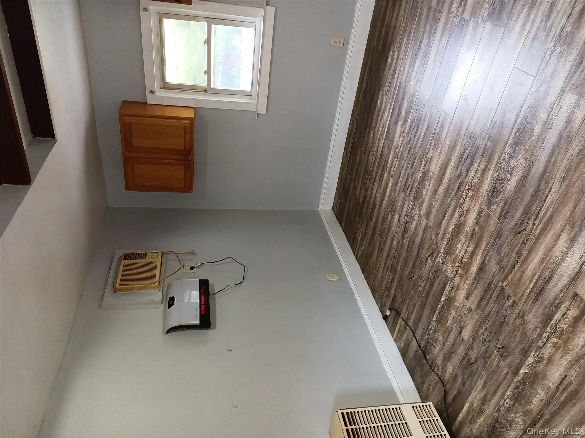 Unfurnished room featuring dark wood-style floors and an AC wall unit Unfurnished room featuring dark wood-style floors and an AC wall unit