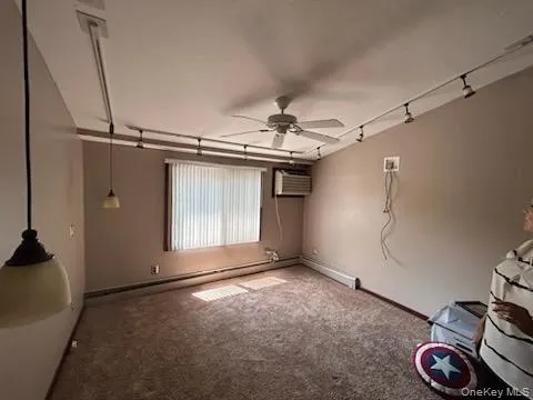 Unfurnished bedroom featuring carpet flooring, a baseboard heating unit, ceiling fan, and a wall mounted air conditioner Unfurnished bedroom featuring carpet flooring, a baseboard heating unit, ceiling fan, and a wall mounted air conditioner