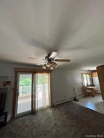 Unfurnished living room with dark colored carpet and ceiling fan Unfurnished living room with dark colored carpet and ceiling fan