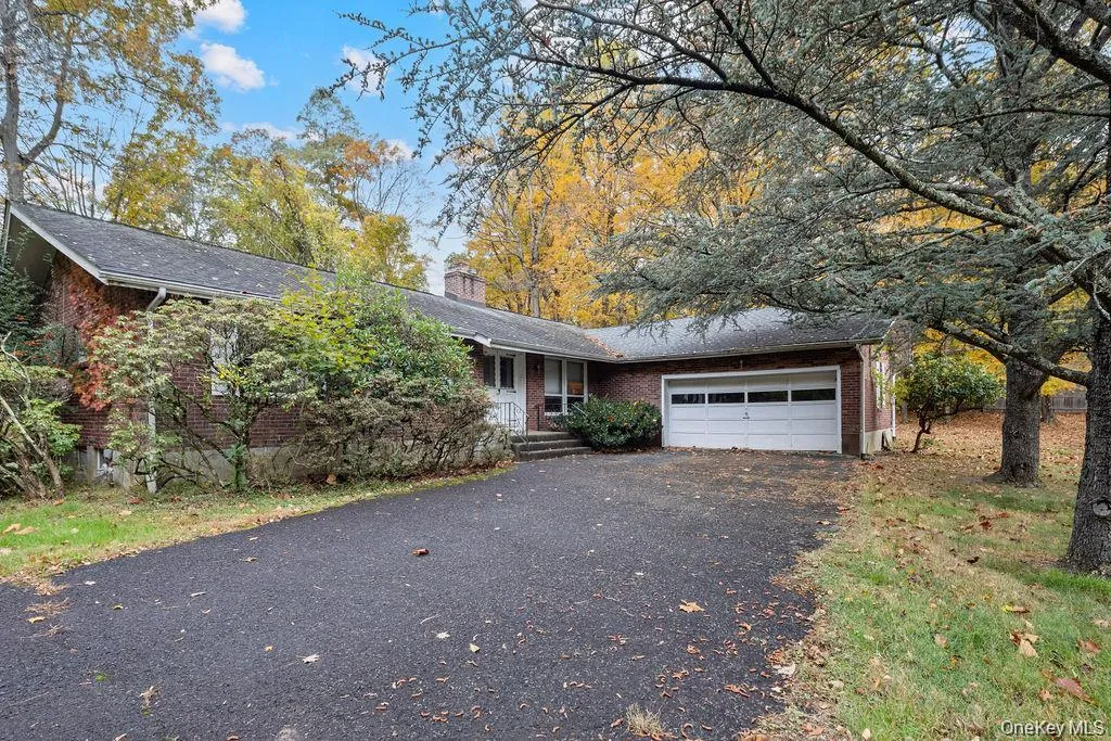 Ranch-style home featuring asphalt driveway, a chimney, brick siding, and an attached garage Ranch-style home featuring asphalt driveway, a chimney, brick siding, and an attached garage