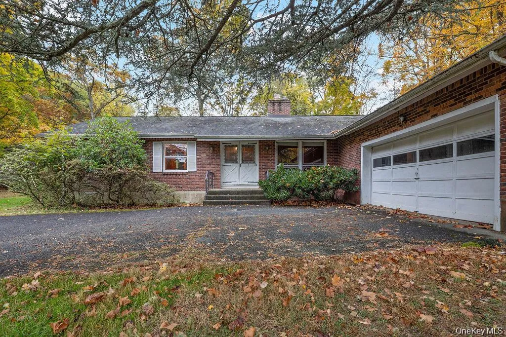 Ranch-style home with brick siding, a chimney, covered porch, and an attached garage Ranch-style home with brick siding, a chimney, covered porch, and an attached garage