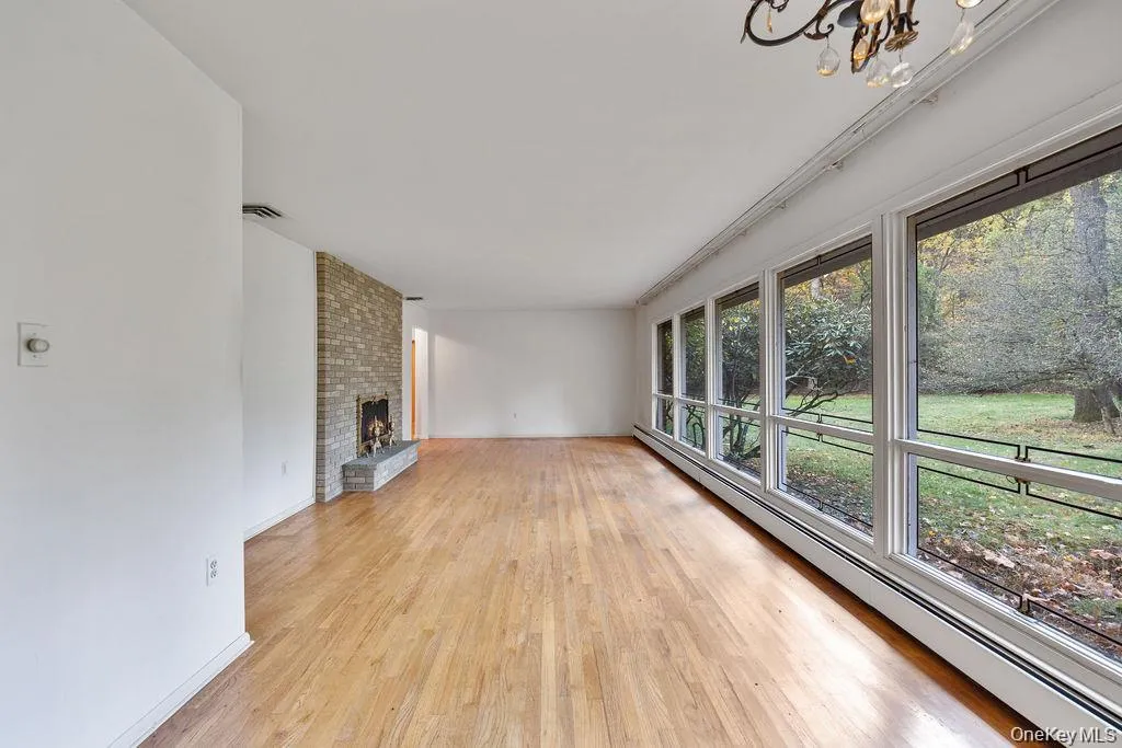 Unfurnished living room with baseboard heating, a fireplace, and light wood-style flooring Unfurnished living room with baseboard heating, a fireplace, and light wood-style flooring