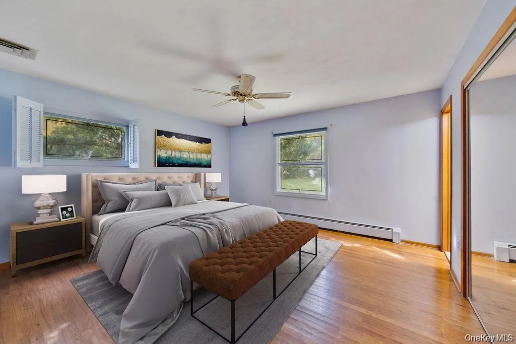 Bedroom featuring a baseboard radiator, a closet, light wood finished floors, and a ceiling fan Bedroom featuring a baseboard radiator, a closet, light wood finished floors, and a ceiling fan