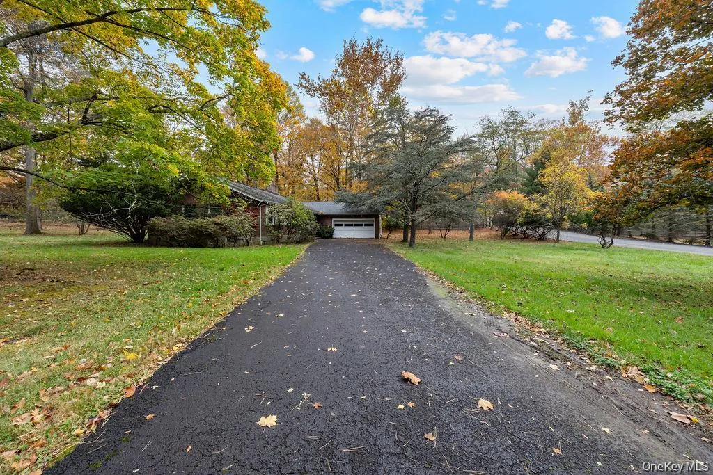 View of front facade featuring a front yard, asphalt driveway, and a garage View of front facade featuring a front yard, asphalt driveway, and a garage