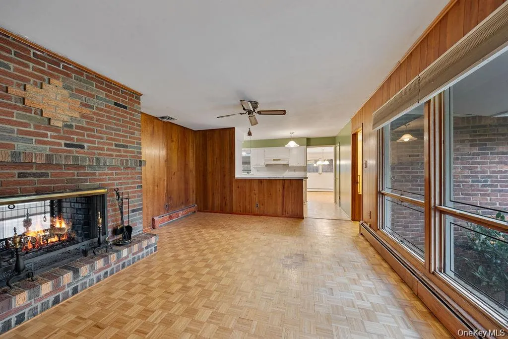 Unfurnished living room with a baseboard heating unit, wooden walls, and a fireplace Unfurnished living room with a baseboard heating unit, wooden walls, and a fireplace
