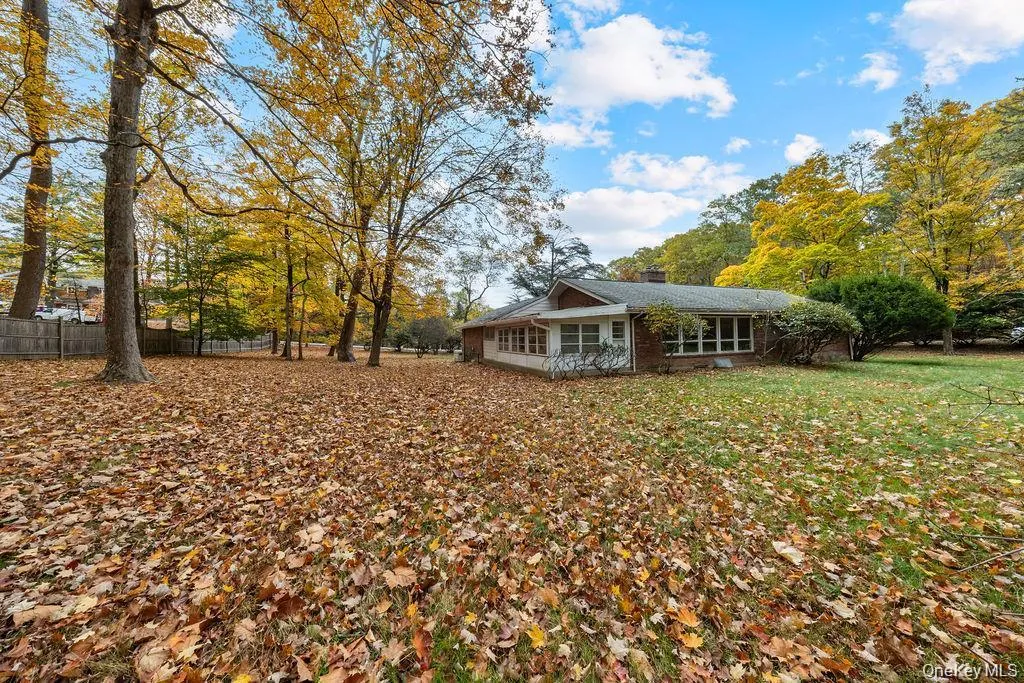 Back of property featuring a chimney, a sunroom, and brick siding Back of property featuring a chimney, a sunroom, and brick siding