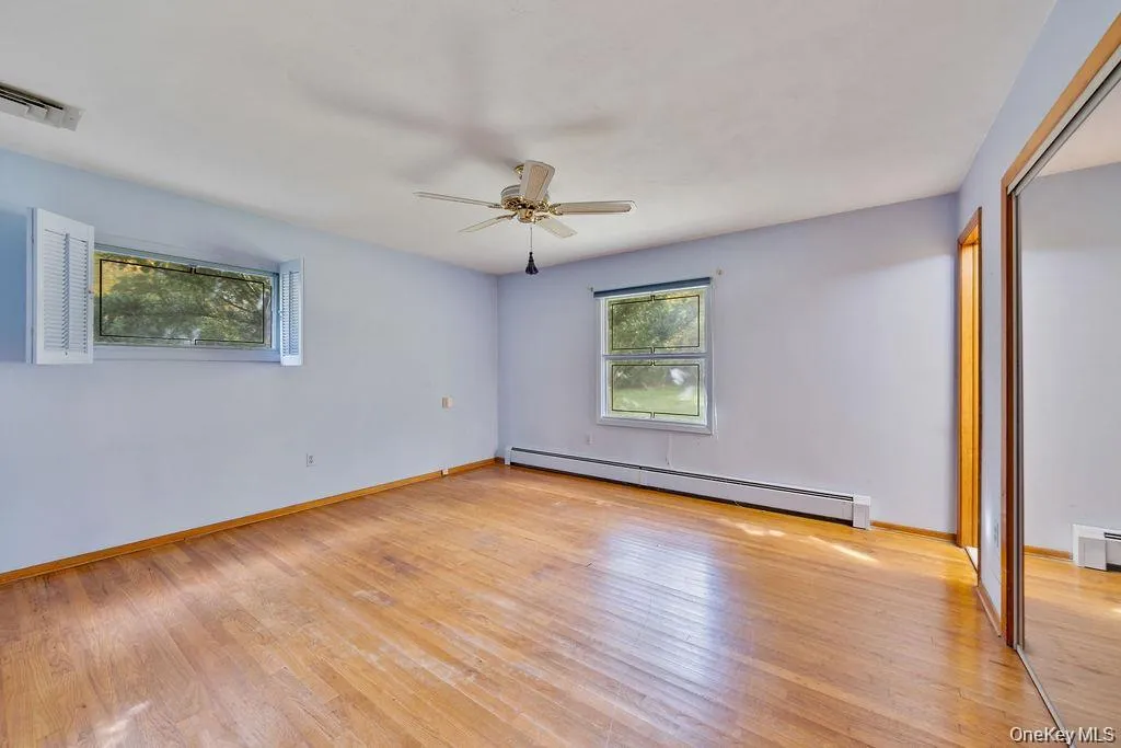 Unfurnished room with baseboard heating, light wood finished floors, and ceiling fan Unfurnished room with baseboard heating, light wood finished floors, and ceiling fan