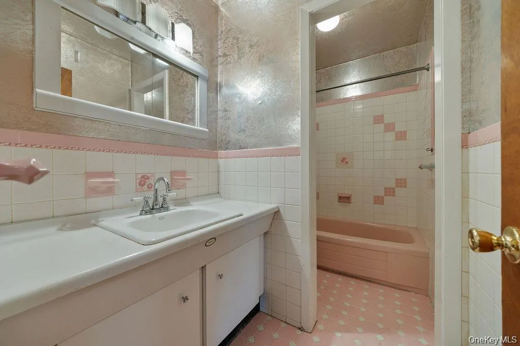 Full bathroom with tile walls, shower / bathtub combination, vanity, and wainscoting Full bathroom with tile walls, shower / bathtub combination, vanity, and wainscoting