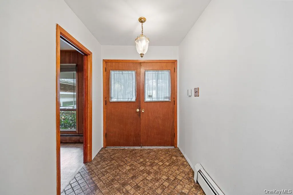 Foyer with a baseboard radiator, plenty of natural light, and brick patterned floors Foyer with a baseboard radiator, plenty of natural light, and brick patterned floors