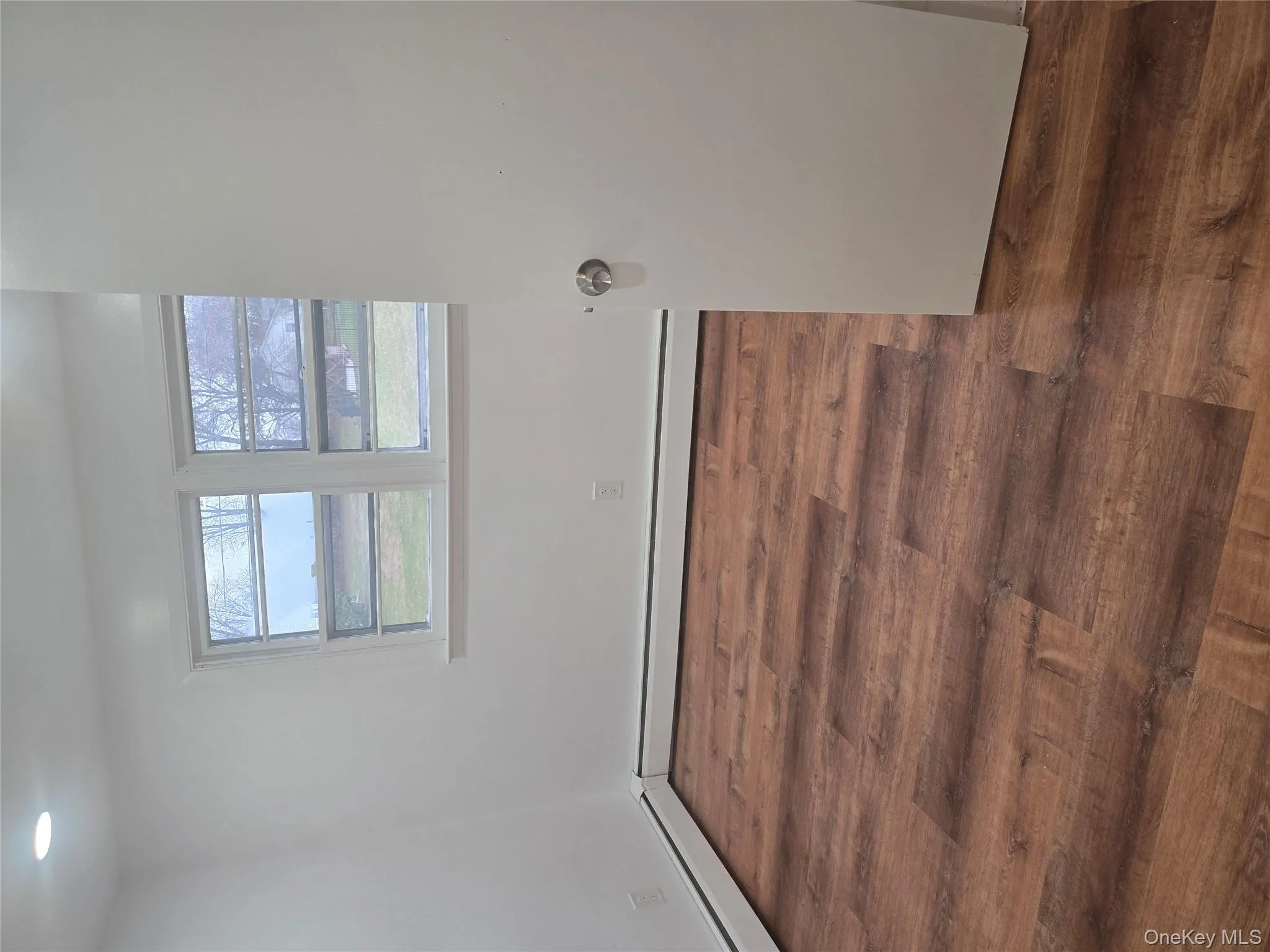 Unfurnished room with dark wood finished floors and baseboard heating Unfurnished room with dark wood finished floors and baseboard heating