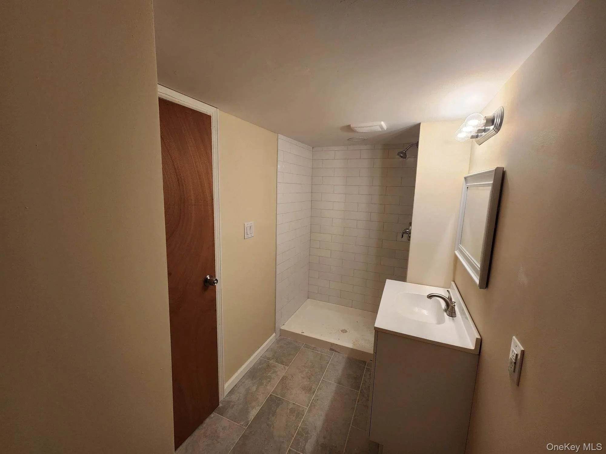 Bathroom with a shower stall, vanity, and dark tile patterned flooring Bathroom with a shower stall, vanity, and dark tile patterned flooring