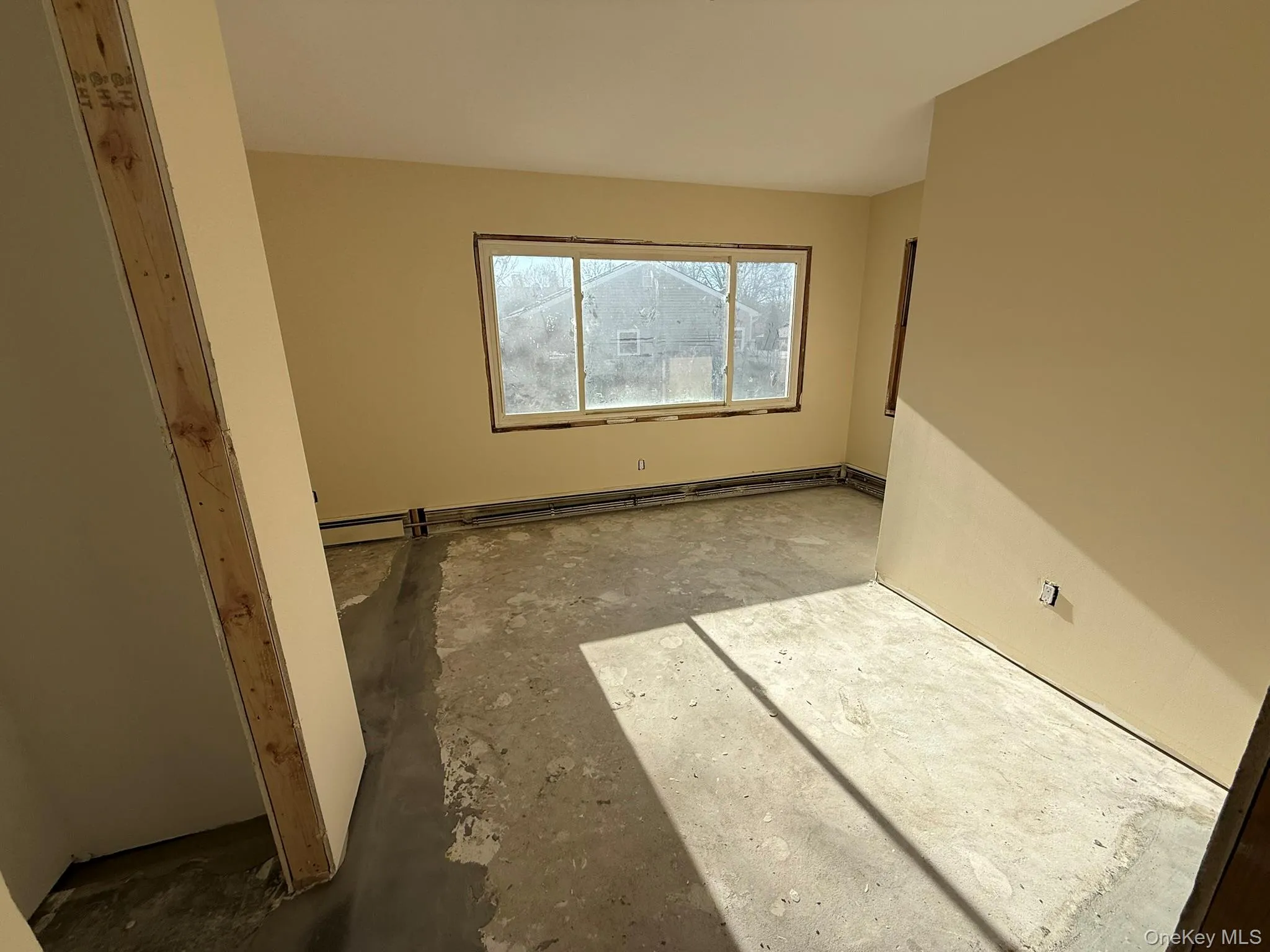 Unfurnished room with unfinished concrete flooring and a baseboard heating unit Unfurnished room with unfinished concrete flooring and a baseboard heating unit