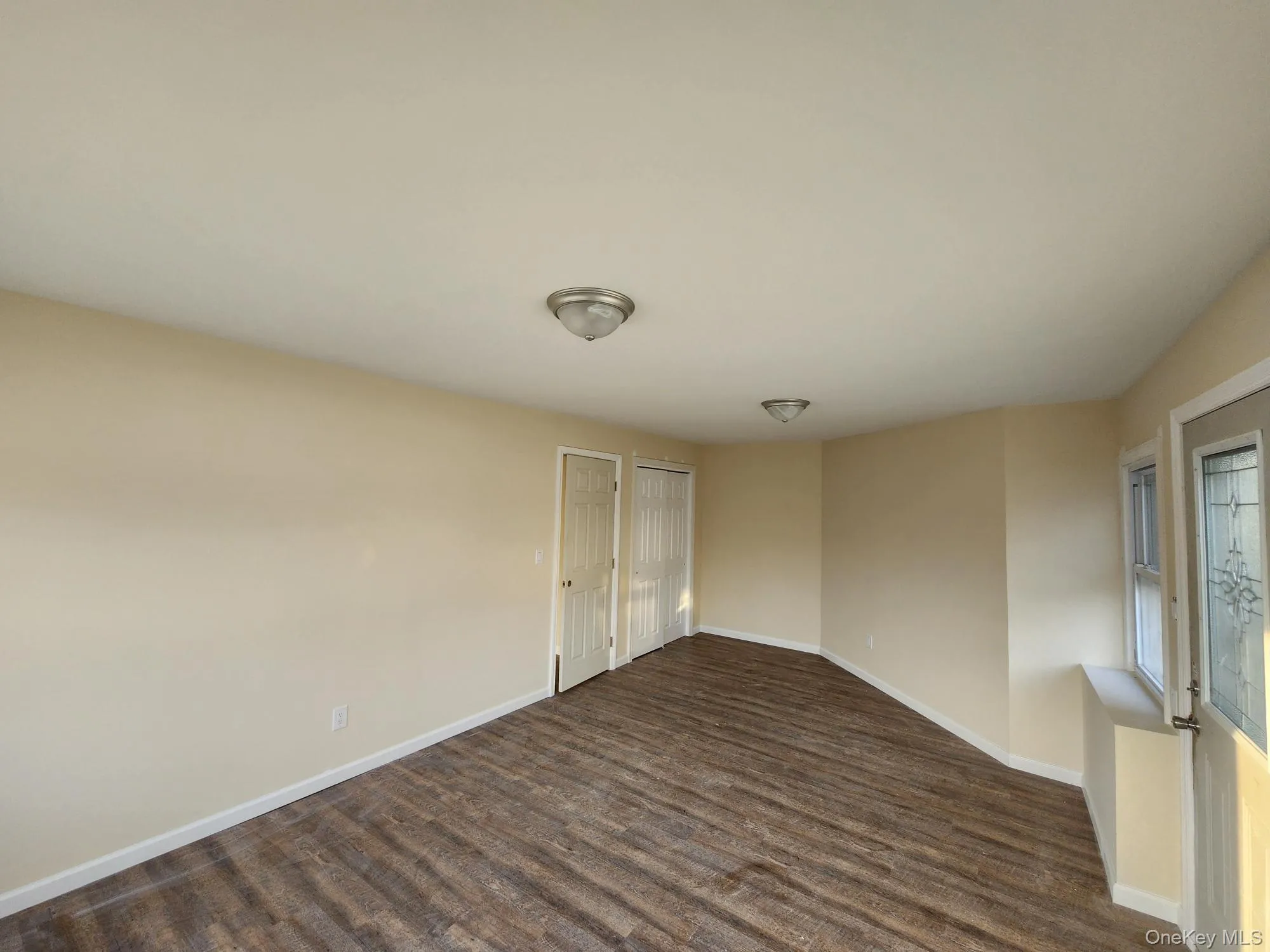 Spare room with baseboards and dark wood-style flooring Spare room with baseboards and dark wood-style flooring