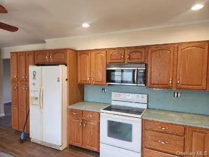 Kitchen with white appliances, brown cabinets, light countertops, and recessed lighting Kitchen with white appliances, brown cabinets, light countertops, and recessed lighting