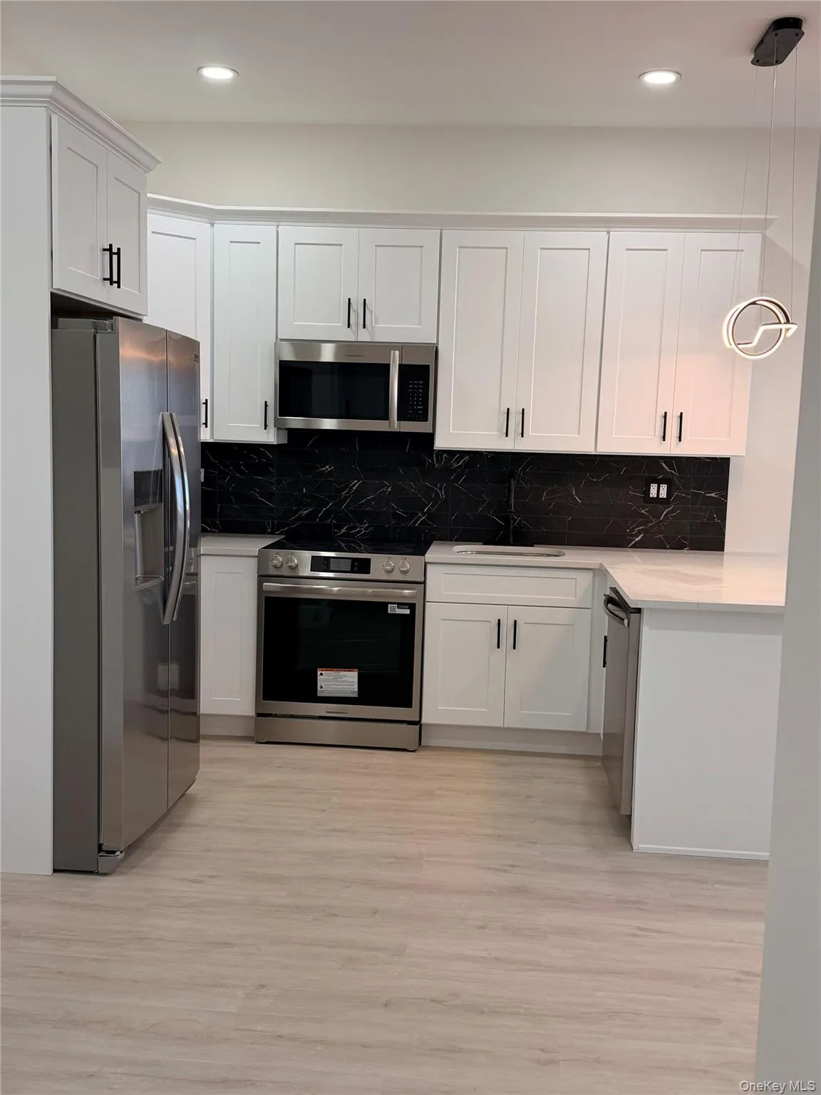 Kitchen with stainless steel appliances, white cabinetry, pendant lighting, light wood finished floors, and recessed lighting Kitchen with stainless steel appliances, white cabinetry, pendant lighting, light wood finished floors, and recessed lighting