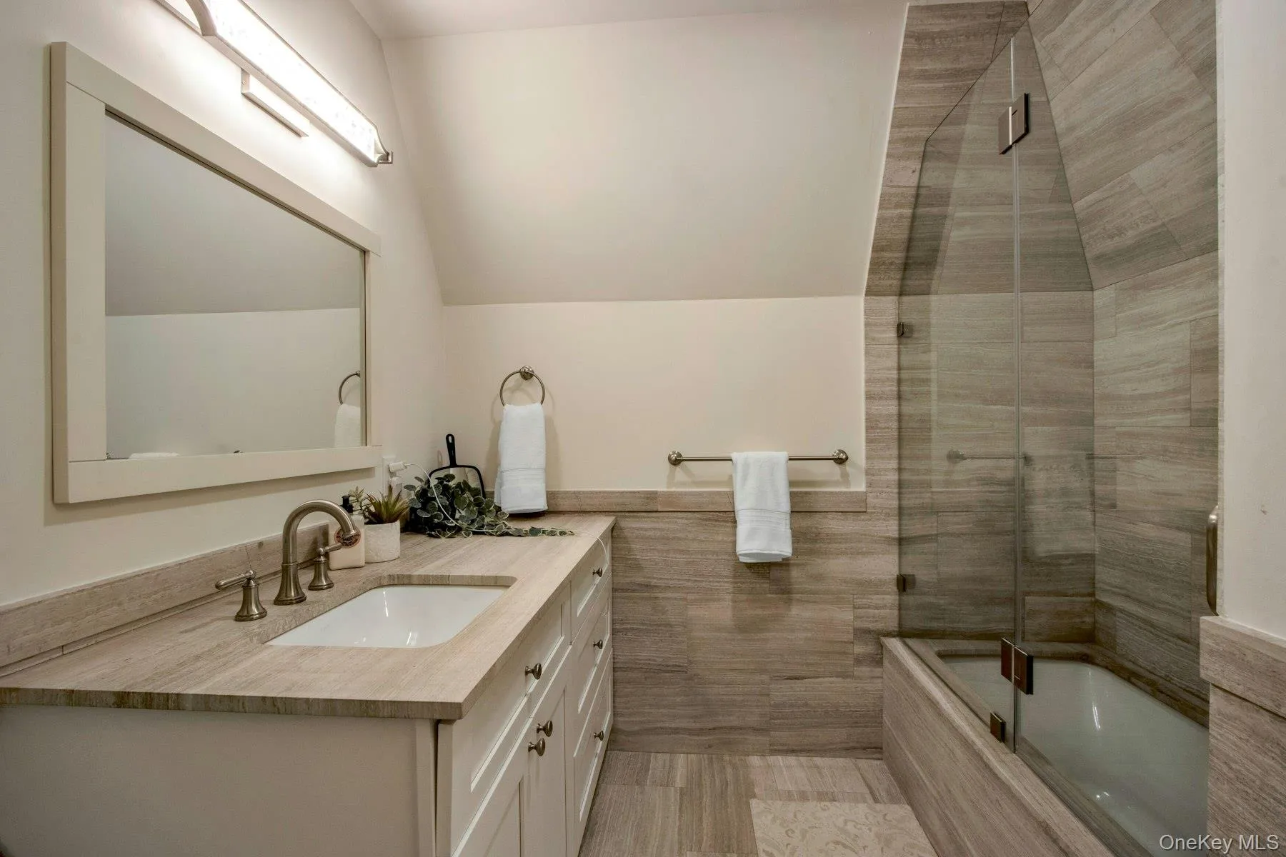 Bathroom with vanity, shower / bath combination with glass door, and vaulted ceiling Bathroom with vanity, shower / bath combination with glass door, and vaulted ceiling