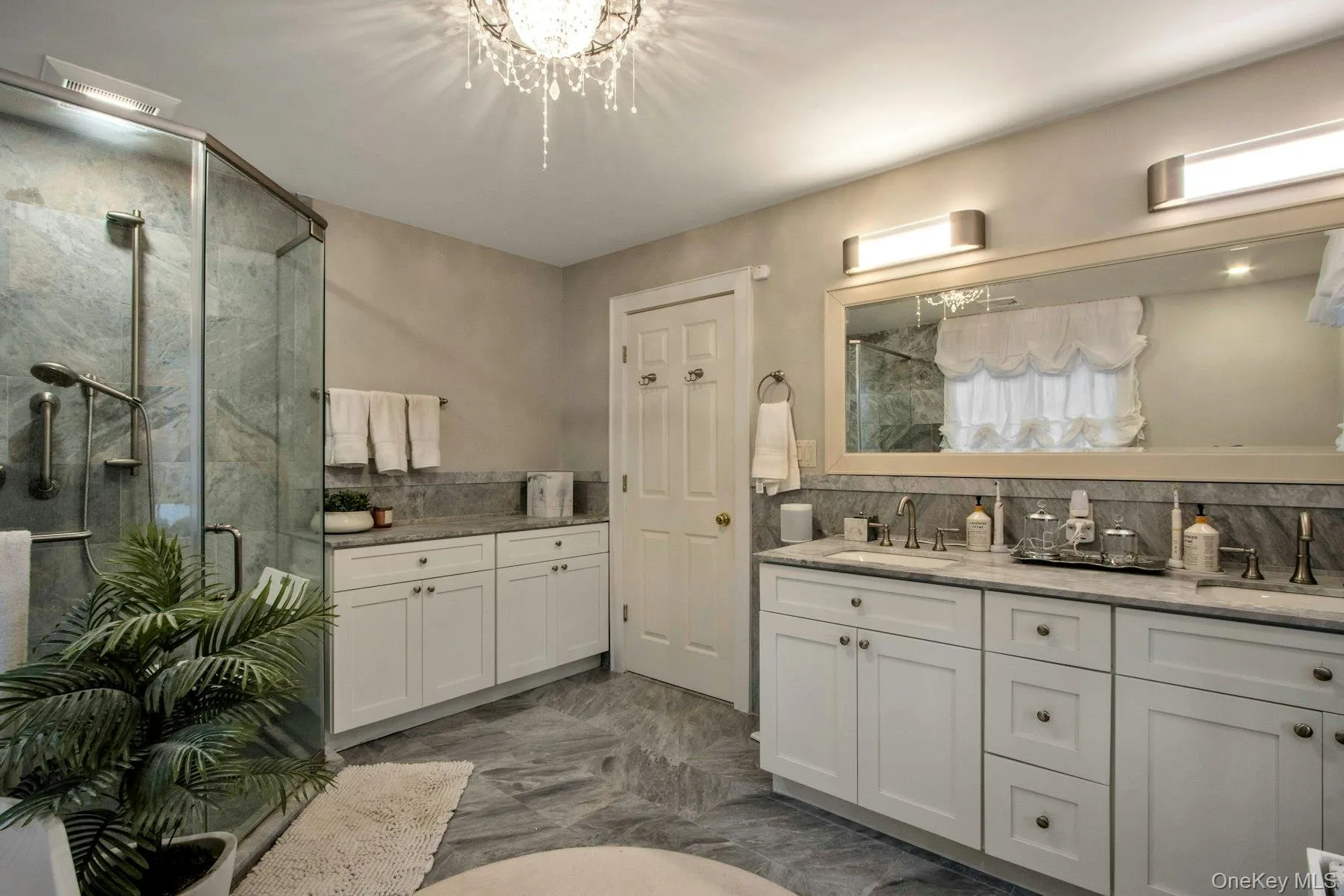 Bathroom featuring decorative backsplash, an enclosed shower, vanity, and an inviting chandelier Bathroom featuring decorative backsplash, an enclosed shower, vanity, and an inviting chandelier