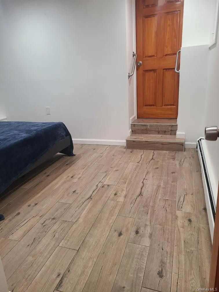 Bedroom featuring baseboard heating and light wood-style flooring Bedroom featuring baseboard heating and light wood-style flooring