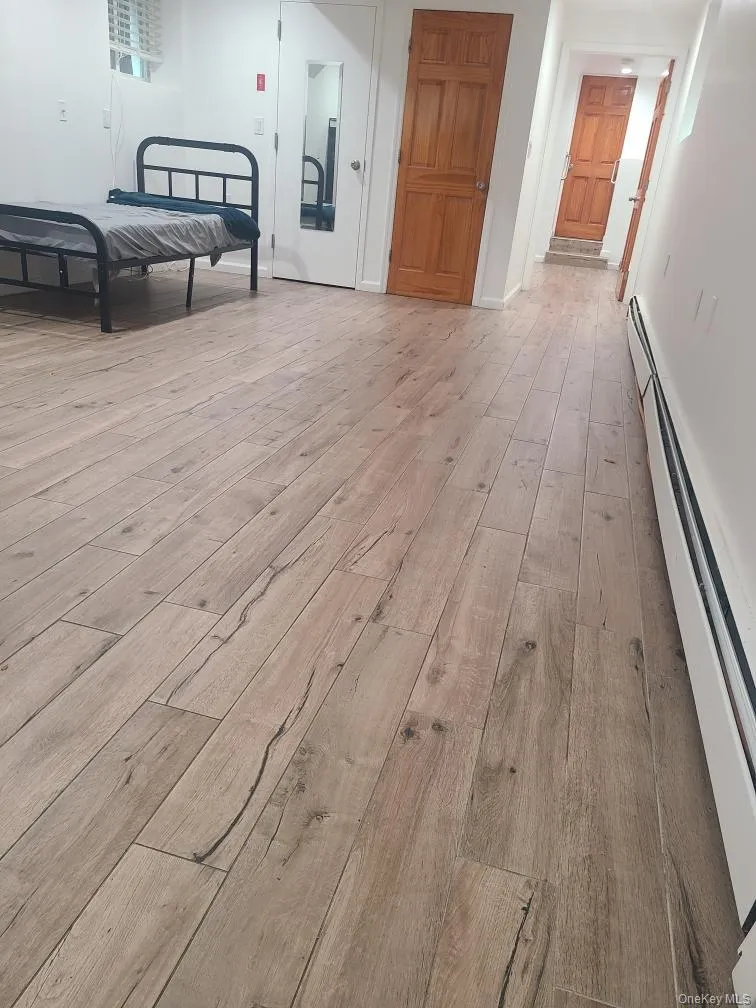 Unfurnished bedroom featuring light wood-style flooring and baseboard heating Unfurnished bedroom featuring light wood-style flooring and baseboard heating