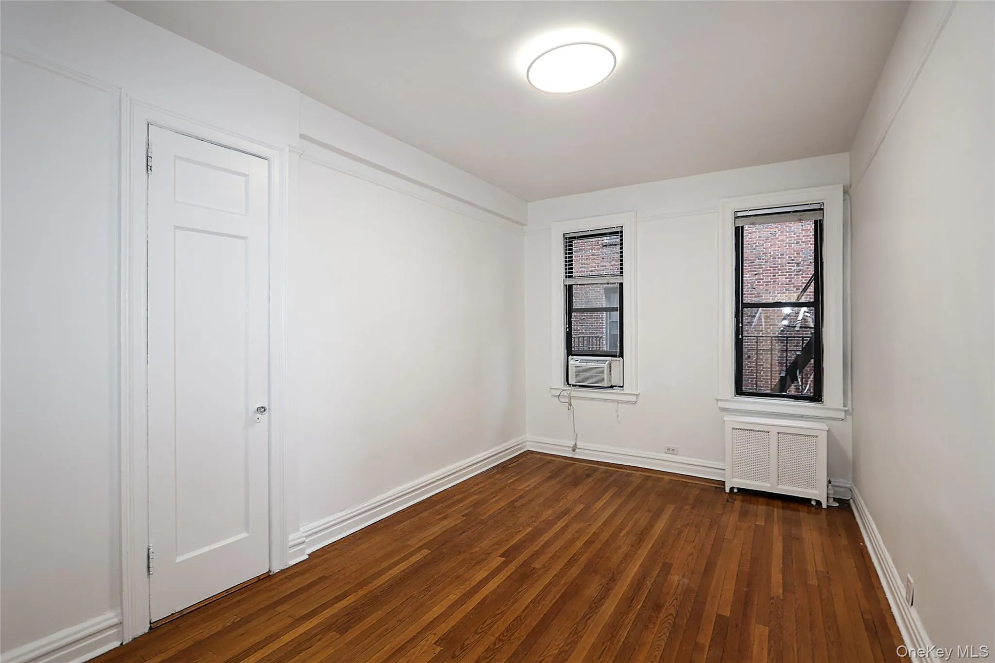 Spare room featuring dark wood-style floors and radiator heating unit Spare room featuring dark wood-style floors and radiator heating unit