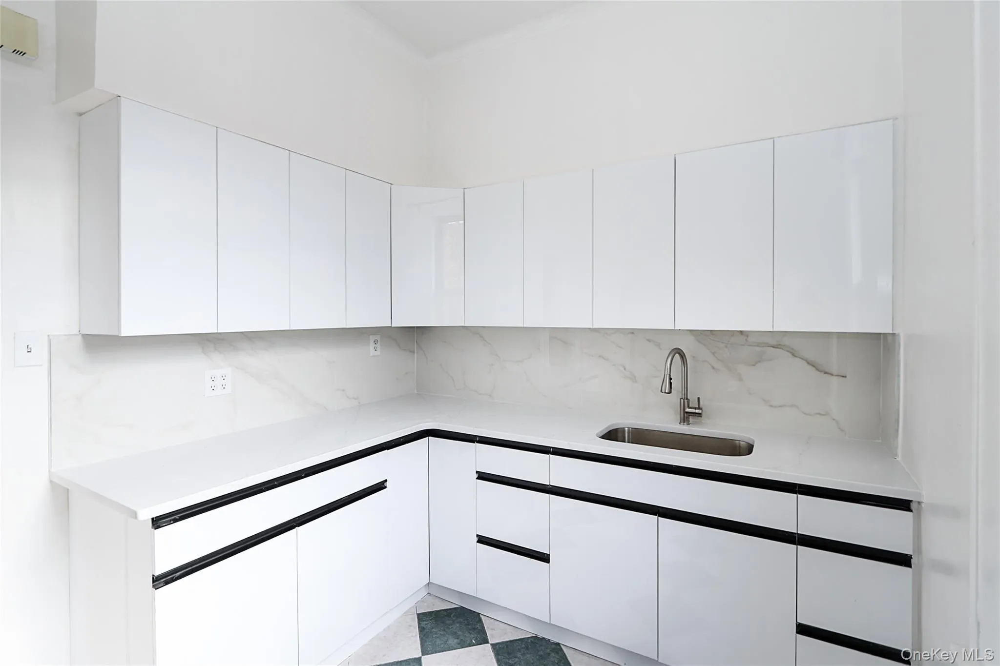 Kitchen featuring white cabinetry, light stone counters, modern cabinets, decorative backsplash, and light floors Kitchen featuring white cabinetry, light stone counters, modern cabinets, decorative backsplash, and light floors