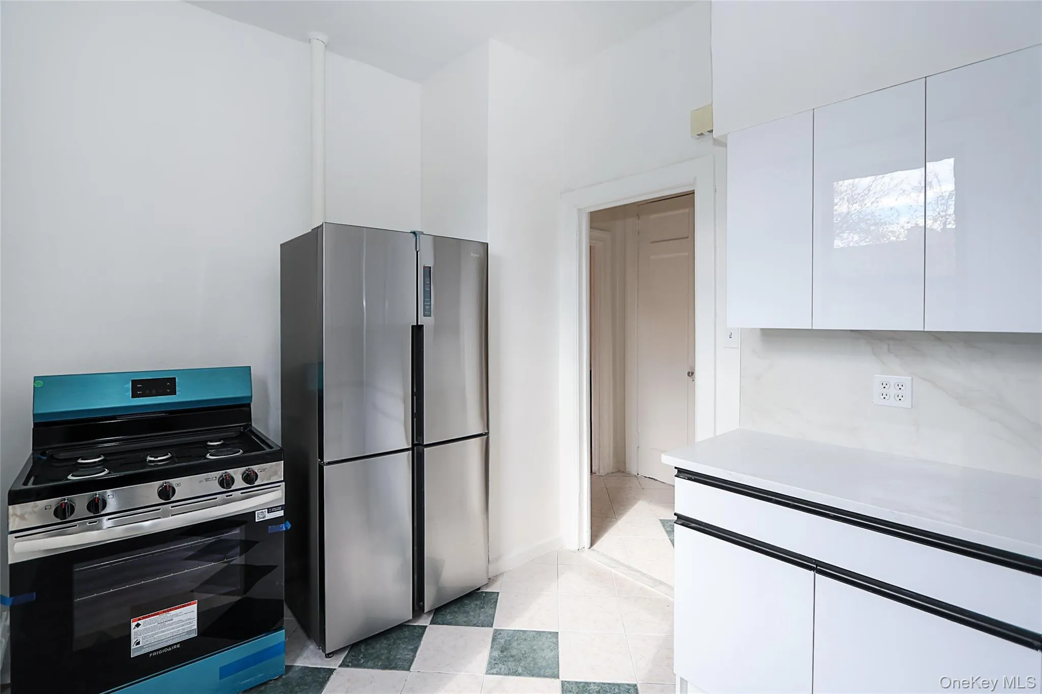 Kitchen featuring appliances with stainless steel finishes, light countertops, white cabinetry, modern cabinets, and light flooring Kitchen featuring appliances with stainless steel finishes, light countertops, white cabinetry, modern cabinets, and light flooring