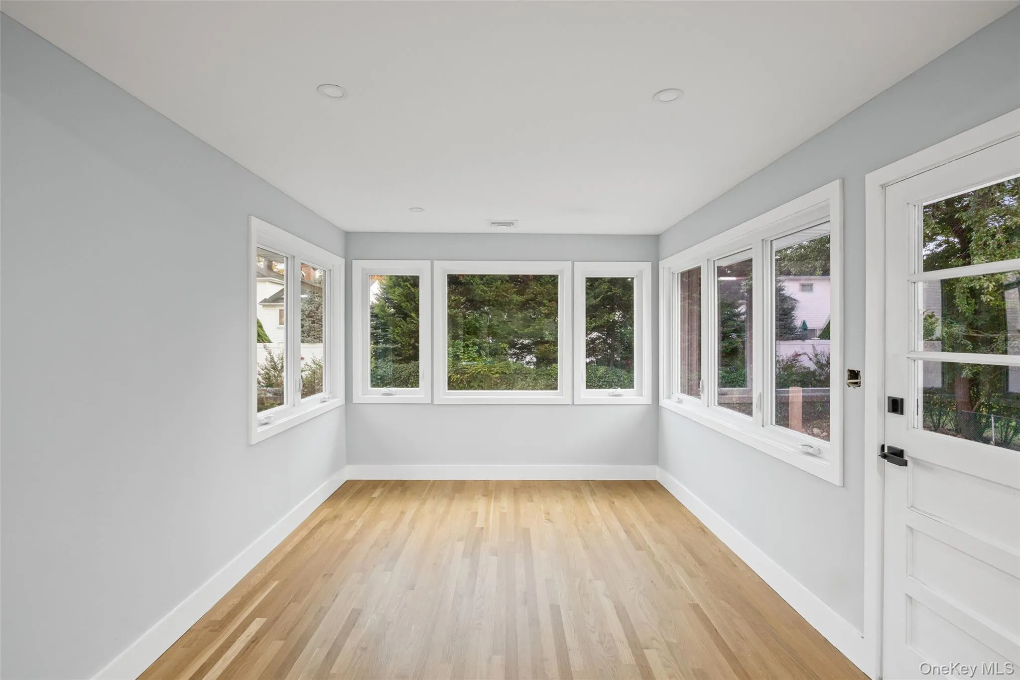 Unfurnished sunroom with wood finished floors, recessed lighting, and french doors Unfurnished sunroom with wood finished floors, recessed lighting, and french doors