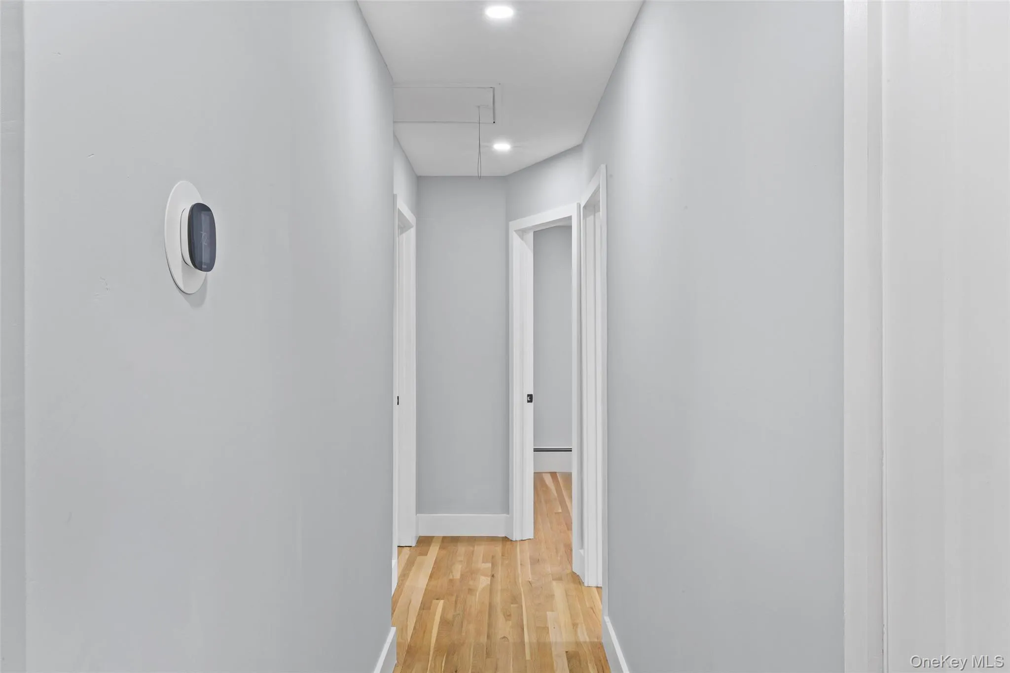 Hallway featuring light wood-style flooring, attic access, and recessed lighting Hallway featuring light wood-style flooring, attic access, and recessed lighting