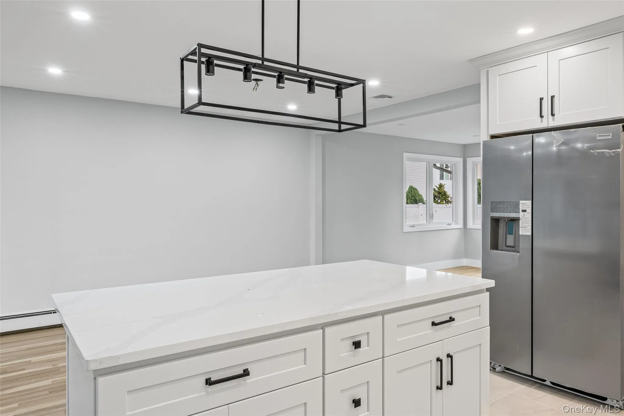 Kitchen featuring white cabinets, stainless steel fridge with ice dispenser, decorative light fixtures, recessed lighting, and light stone countertops Kitchen featuring white cabinets, stainless steel fridge with ice dispenser, decorative light fixtures, recessed lighting, and light stone countertops