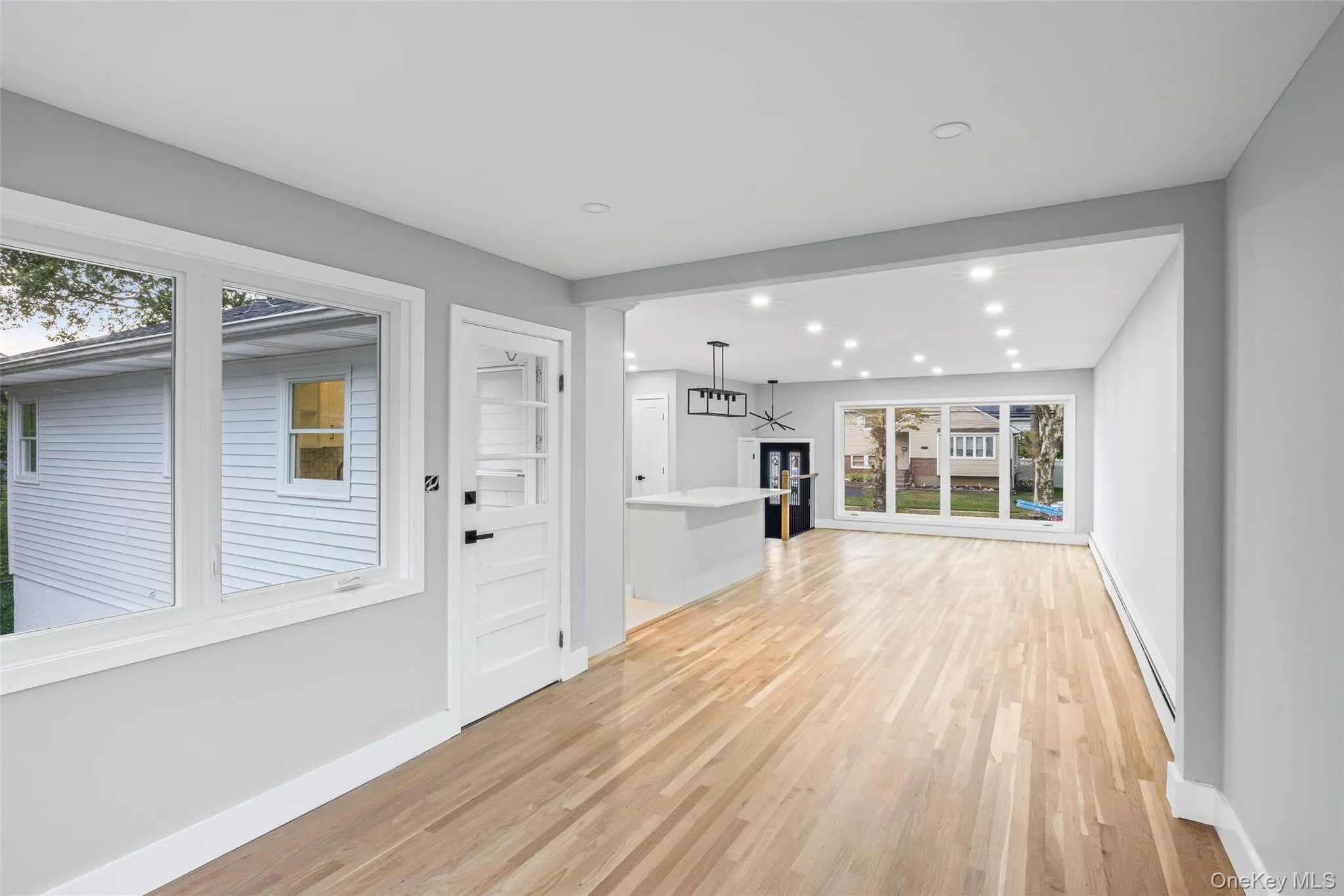 Unfurnished living room featuring light wood-type flooring, a baseboard radiator, and recessed lighting Unfurnished living room featuring light wood-type flooring, a baseboard radiator, and recessed lighting
