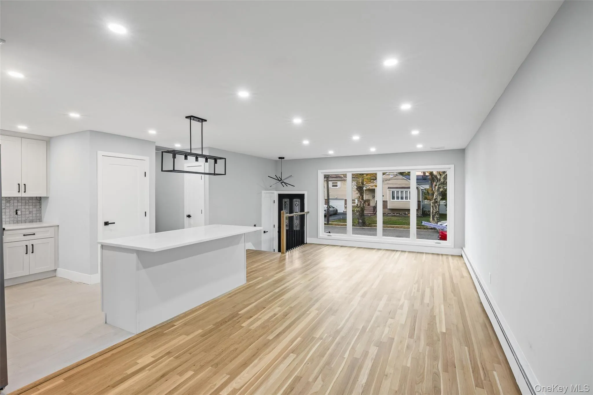 Unfurnished living room with a baseboard heating unit, light wood-type flooring, and recessed lighting Unfurnished living room with a baseboard heating unit, light wood-type flooring, and recessed lighting