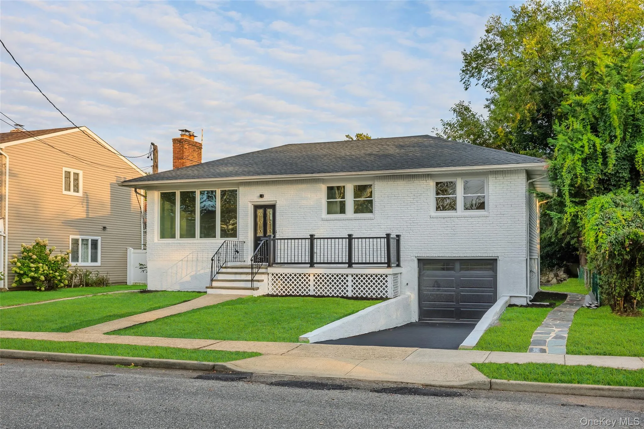Tri-level home featuring a front yard, brick siding, a shingled roof, and a chimney Tri-level home featuring a front yard, brick siding, a shingled roof, and a chimney